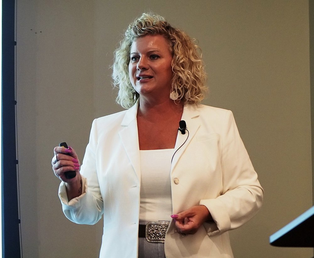 Amanda L. Townley speaking on stage, mid-gesture, wearing a lavalier microphone.